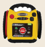 A large yellow and red jump starter covered in dials, switches and warning labels.